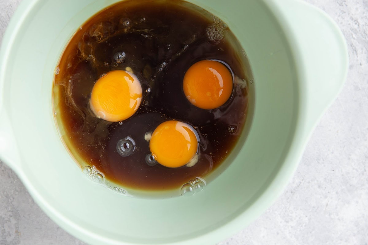 Eggs, oil, and pure maple syrup in a mixing bowl to make chocolate bread.