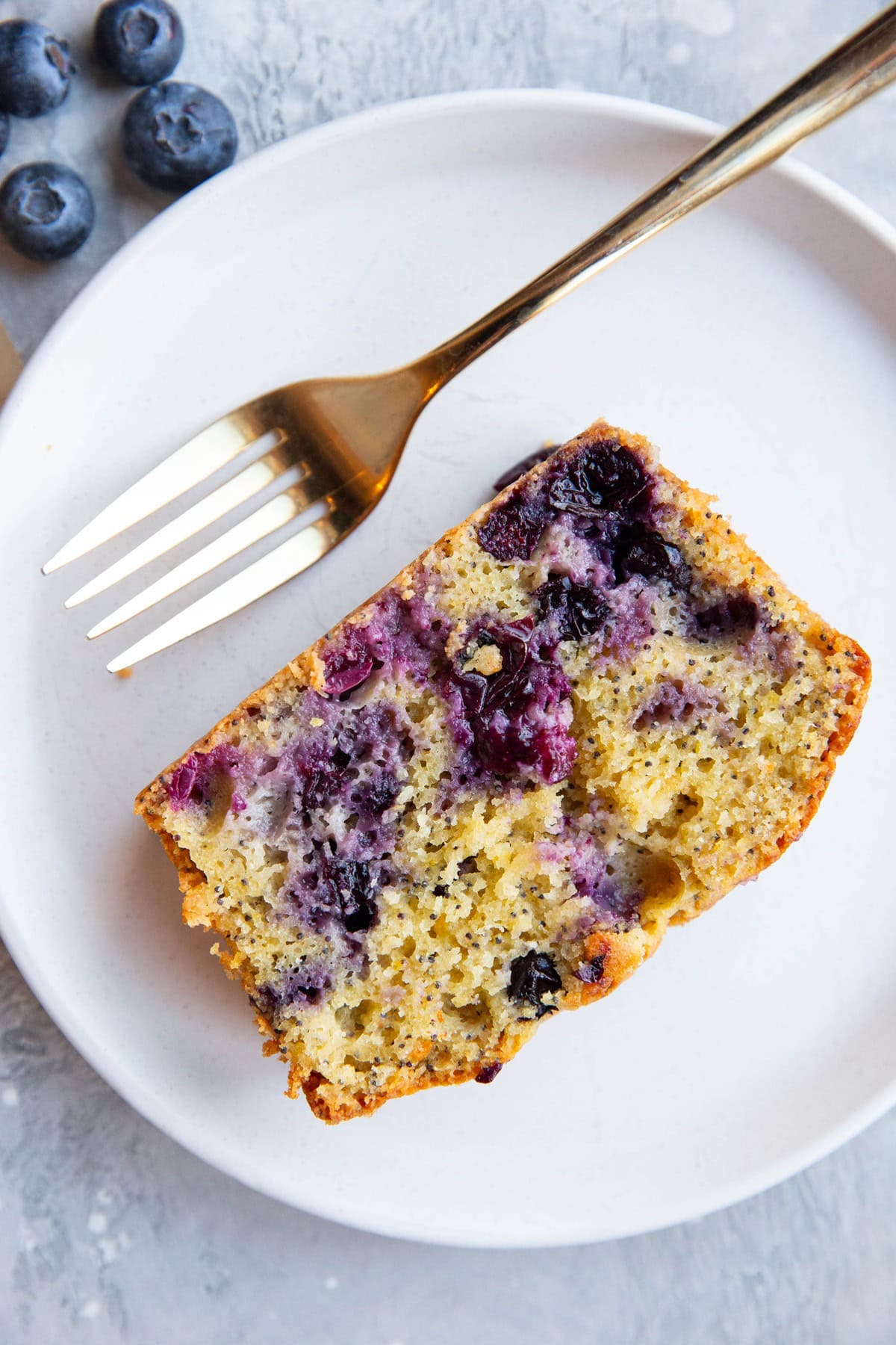 Slice of lemon poppy seed blueberry bread on a plate.