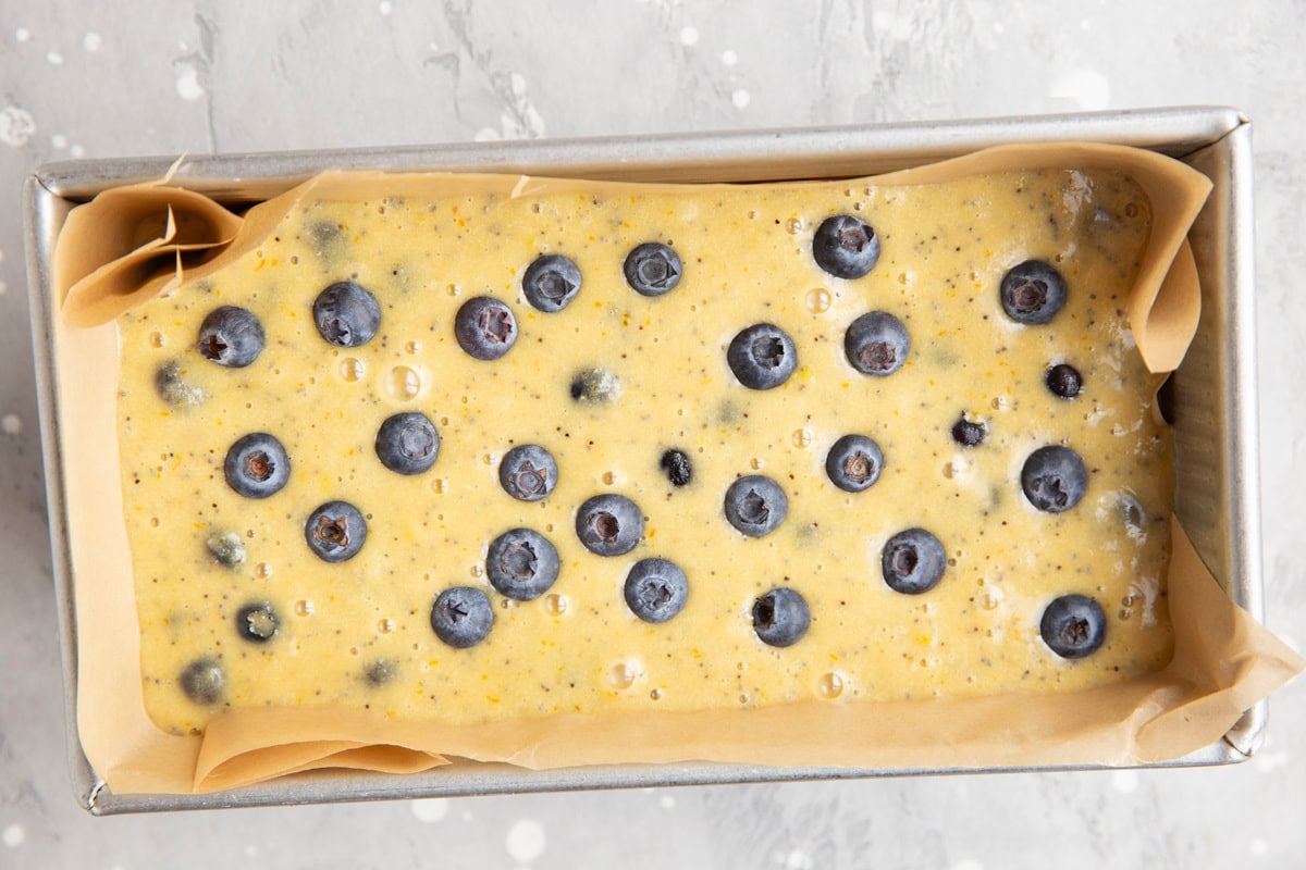 Loaf pan with lemon blueberry bread batter inside.