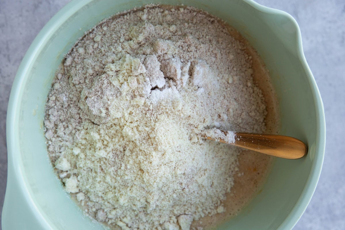 Mixing bowl with dry ingredients on top of wet ingredients to make a breakfast cake.