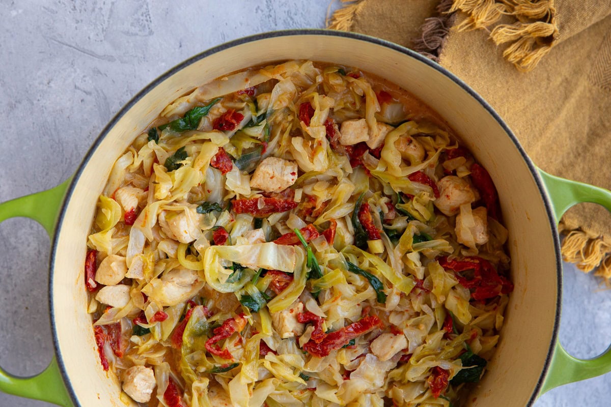 Large pot of chicken, cabbage, and sun-dried tomato sauce.