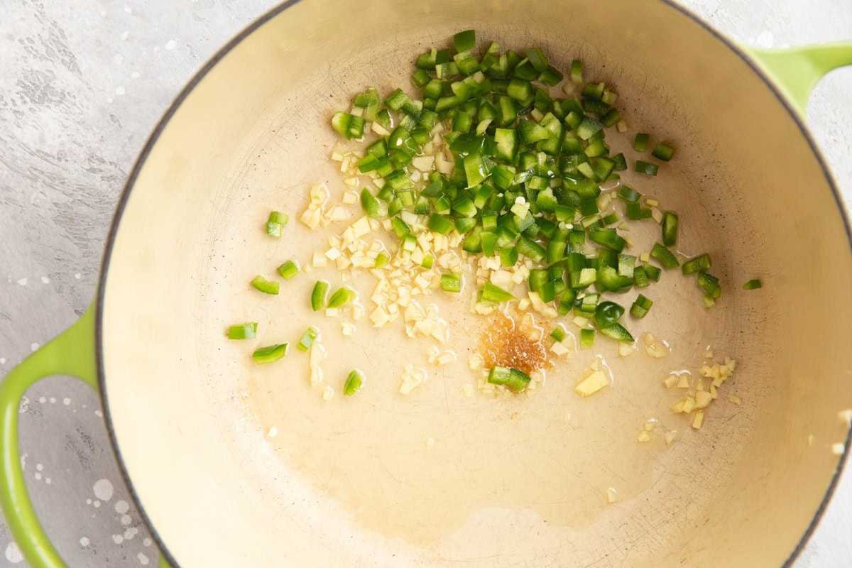 Large pot with garlic, chilis and seasonings cooking in oil.