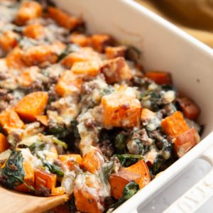 Sweet potato, ground beef, and spinach in a casserole dish.